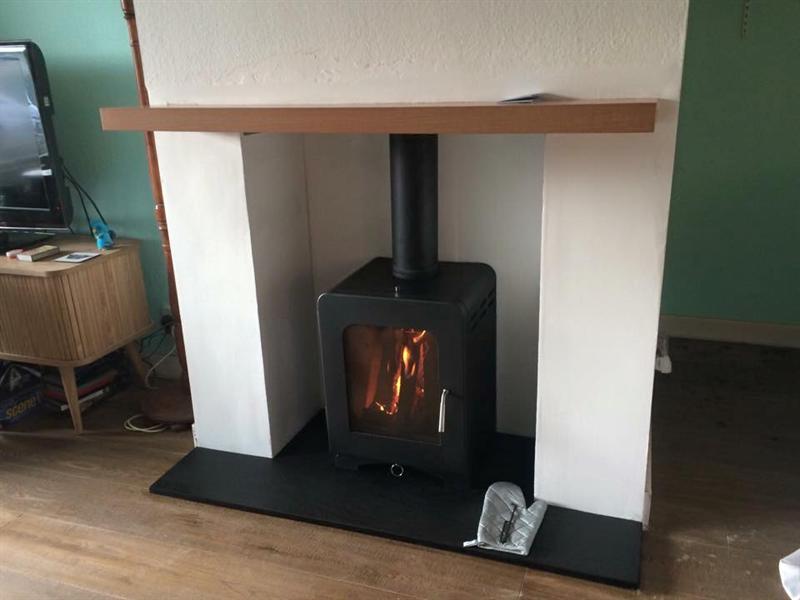 Log burner installed on a slate hearth with oak mantel